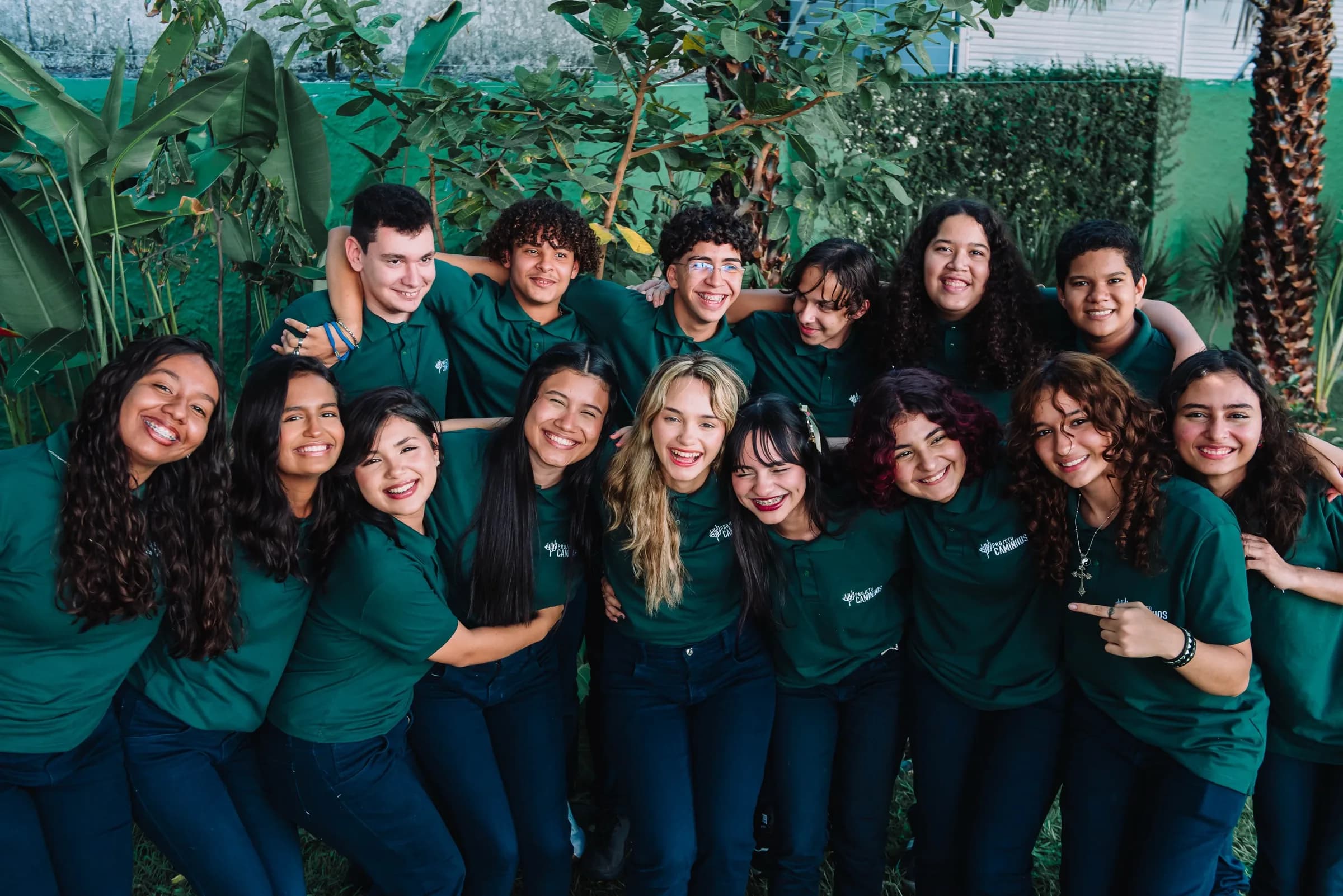 Bolsistas do Projeto Caminhos reunidos e sorrindo, de camisa verde do projeto